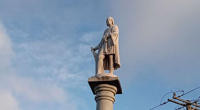 Imagem enquadra a estátua de Cristóvão Colombo sobre uma pilastra