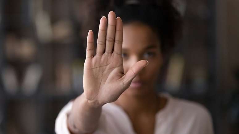 Imagem mostra uma mulher negra que está com a mão levantada