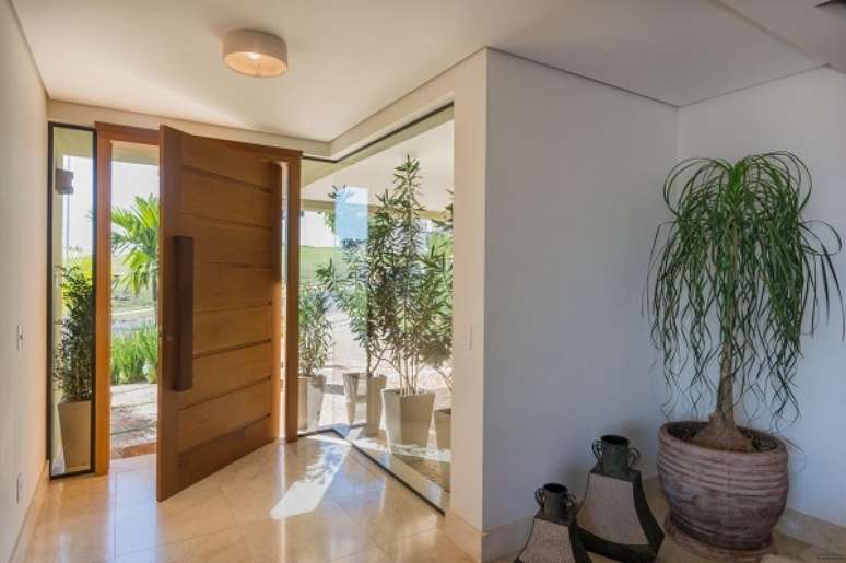 39. Hall de entrada simples decorado com plantas e vasos grandes &ndash; Foto Jannini Sagarra Arquitetura