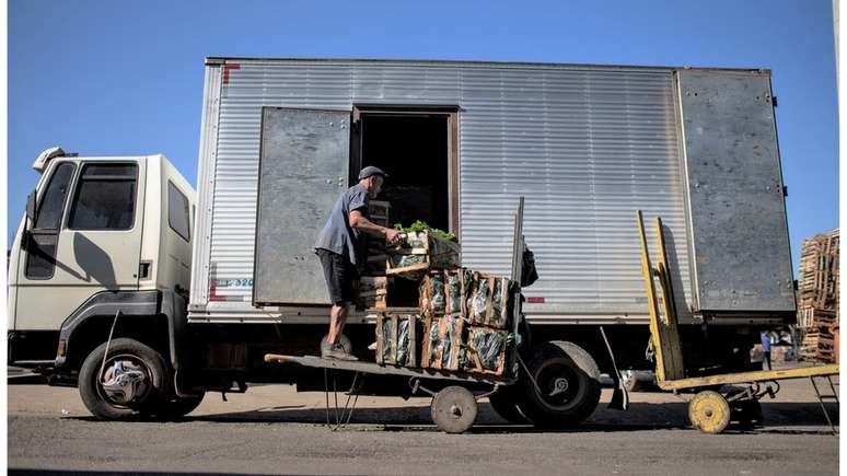 Caminhoneiro colocando produtos no veículo