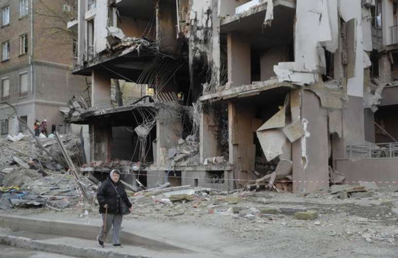 Mulher caminha diante de prédio residencial em Kiev, capital da Ucrânia, bombardeado pela Rússia