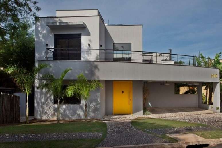 3. Casa com fachada cinza e porta de entrada amarela. Fonte: Guardini Stancati Arquitetura + Designer