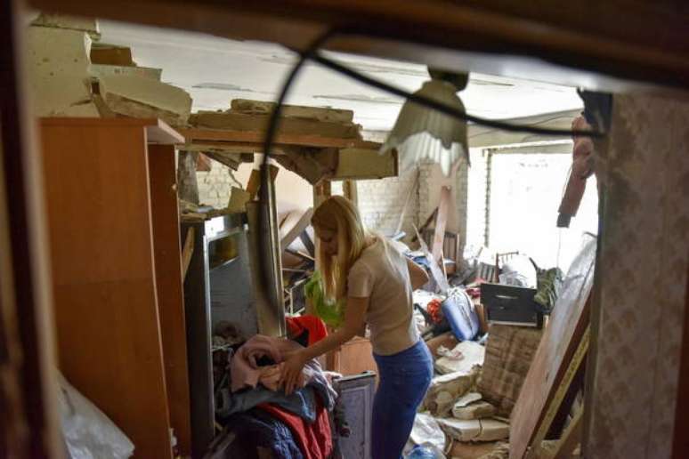 Uma ucraniana recolhendo o resto de alguns pertences em um apartamento destruído em Borodyanka