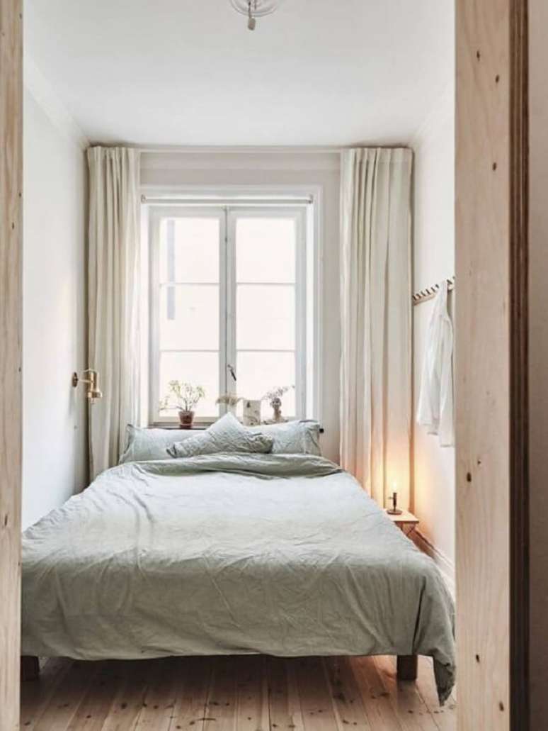40. Projeto de quarto com piso de madeira e cama embaixo da janela. Fonte: HomeAdore