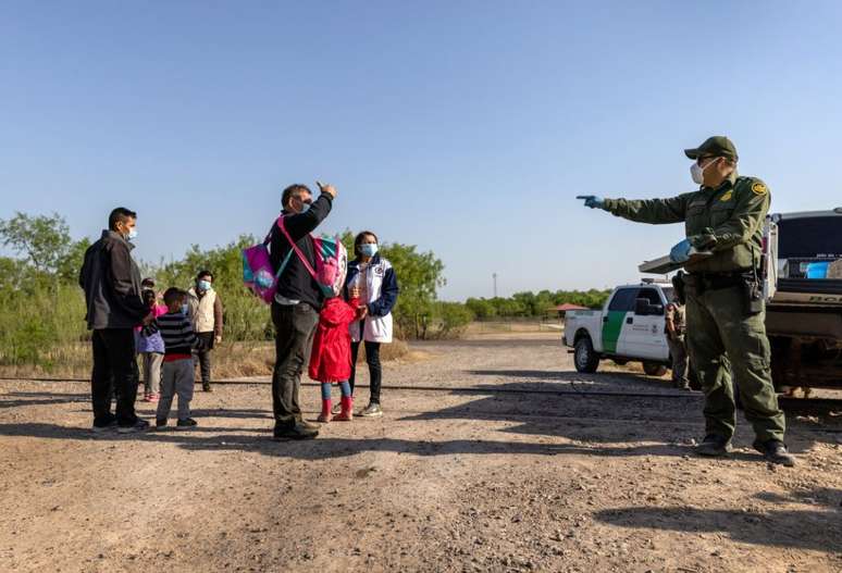 Um agente de patrulha de fronteira dos EUA conversa com uma família venezuelana que atravessou a fronteira do México. A foto foi tirada em 26 de março em Peñitas, Texas