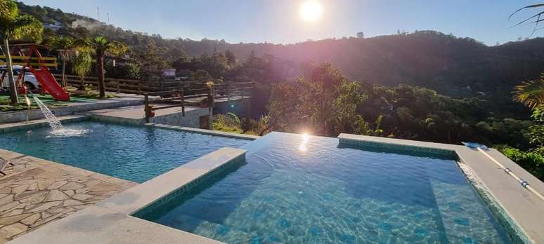 A piscina de borda infinita com vista para a serra se divide em uma porção mais rasa e outra mais funda.