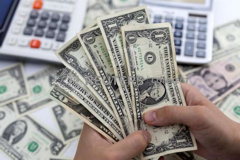 Mulher segura notas de dólar norte-americano nesta ilustração de 30 de maio de 2022 REUTERS/Dado Ruvic