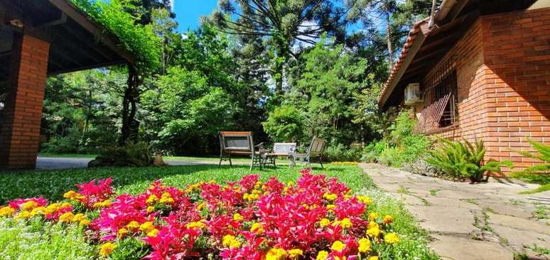 Jardins floridos e araucárias cercam a acomodação.