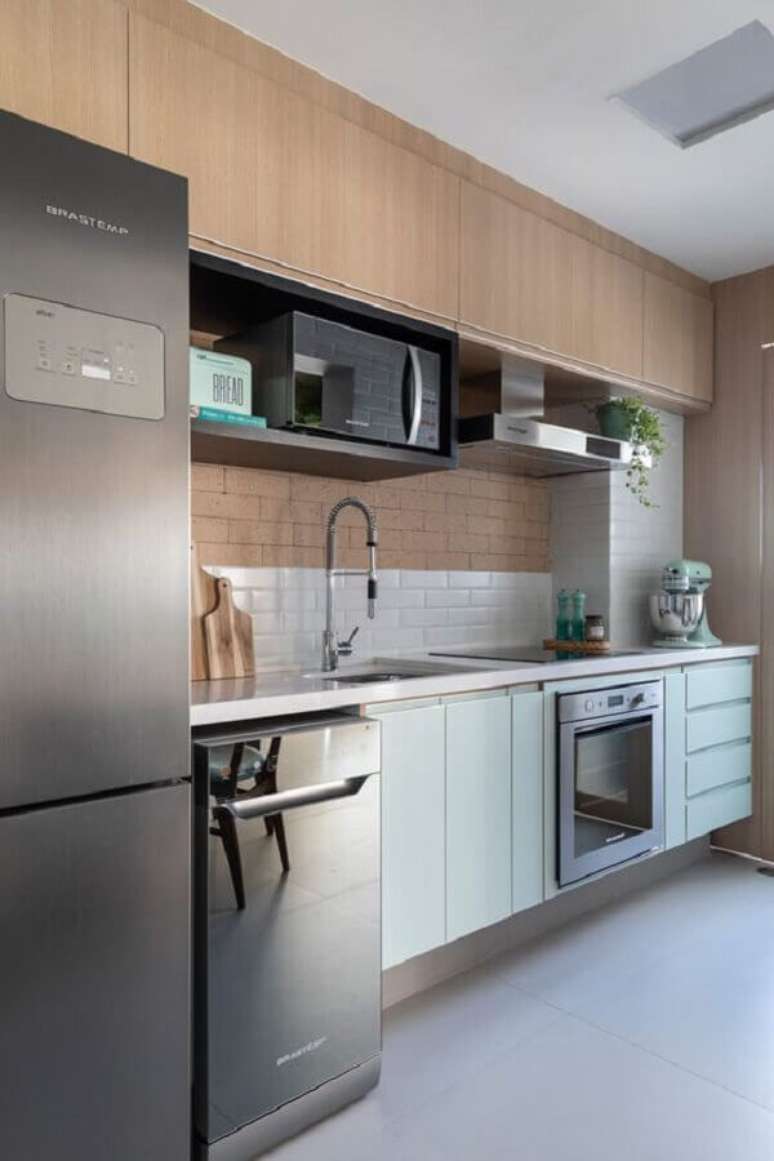 32. Cozinha moderna decorada com arm&aacute;rio a&eacute;reo de madeira e gabinete em verde pastel &ndash; Foto: Marina Carvalho