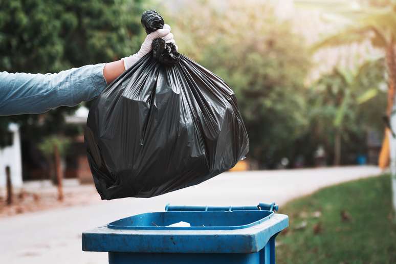 hand holding garbage black bag putting in to trash; Shutterstock ID 1265319334; Purchase Order: 2529; Job: bag; Client/Licensee: spy