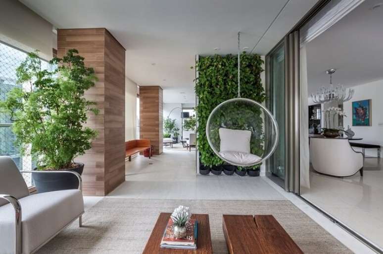 55. Varanda ampla com parede de plantas, balanço e móveis de jardim. Fonte: Luciana Tomas