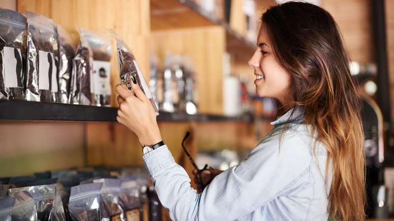 Mulher escolhendo café para comprar em prateleira