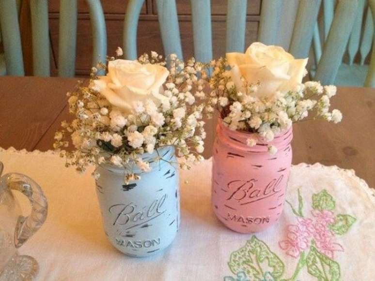 69- Sobre a mesa do chá revelação, potes rosa e azul acomodam rosas e mosquitinhos brancos. Fonte: Casa e Festa