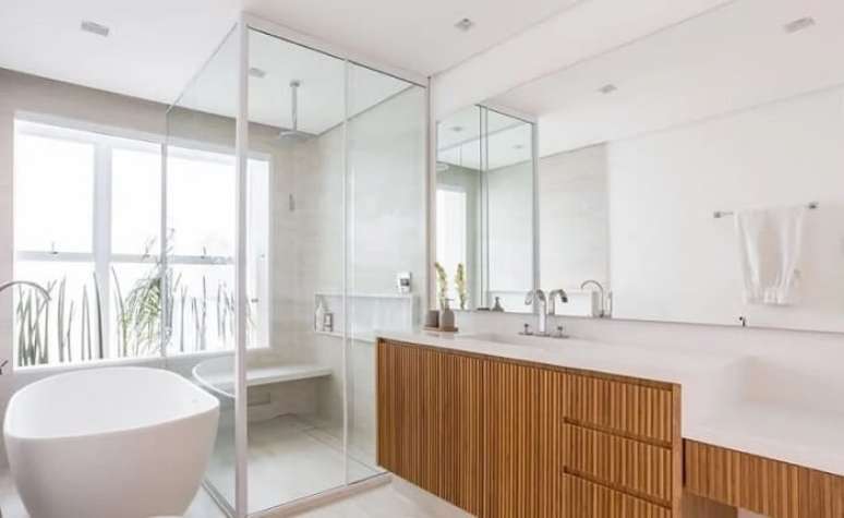 3. Banheiro clean com arm&aacute;rio de madeira e chuveiro de teto. Fonte: Figueiredo Fischer Arquitetos