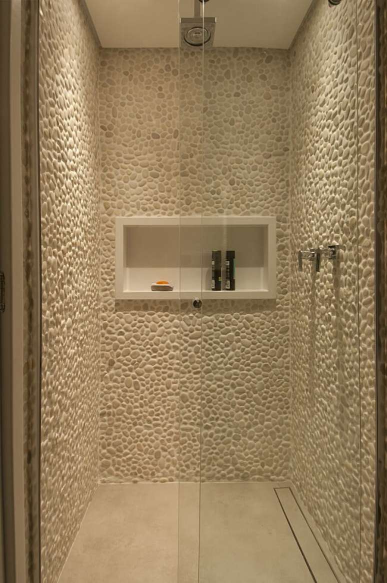 61. Banheiro com parede revestida de seixos e chuveiro de teto. Fonte: Bruno Moraes Arquitetura e Interiores