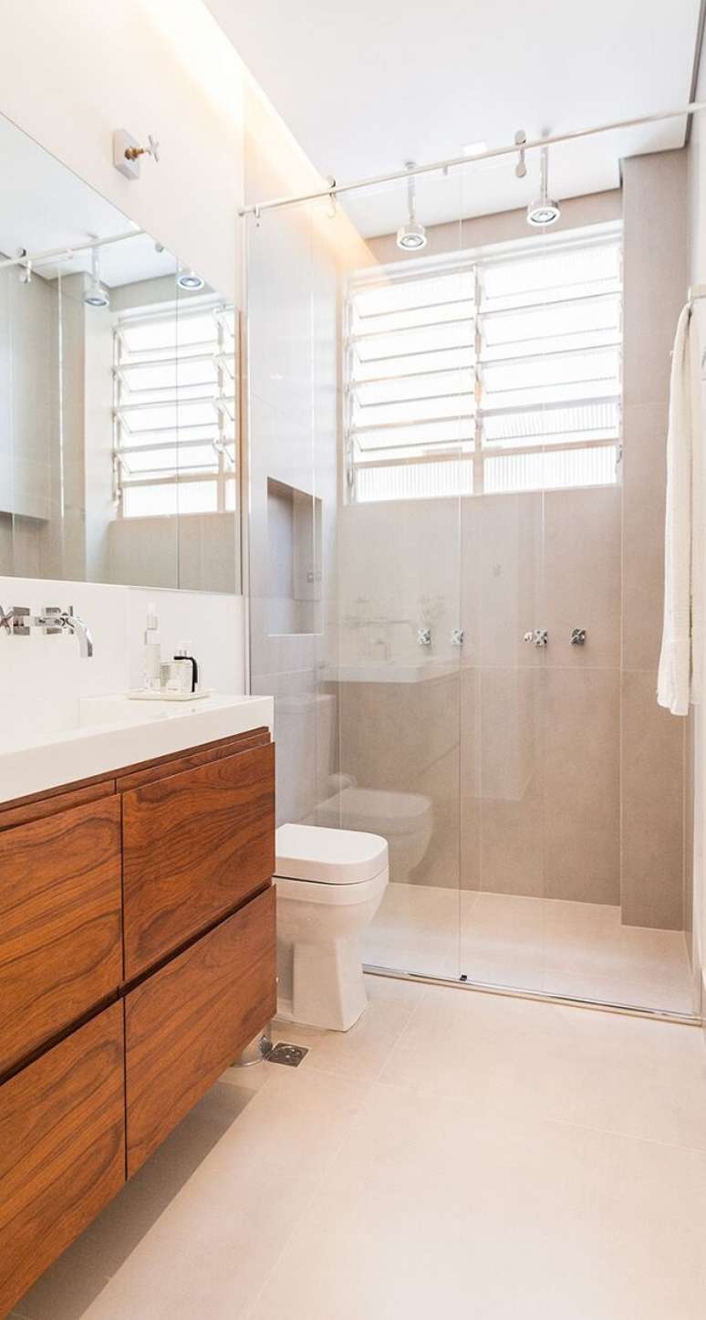 71. Banheiro com arm&aacute;rio de madeira e chuveiro de teto. Fonte: Studio Scatena Arquitetura