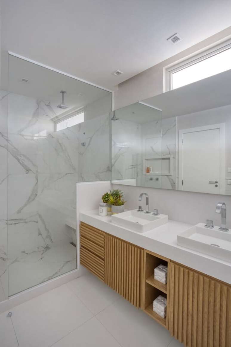 75. Banheiro clean com gabinete de madeira ripada e chuveiro de teto. Fonte: Bruno Cortina