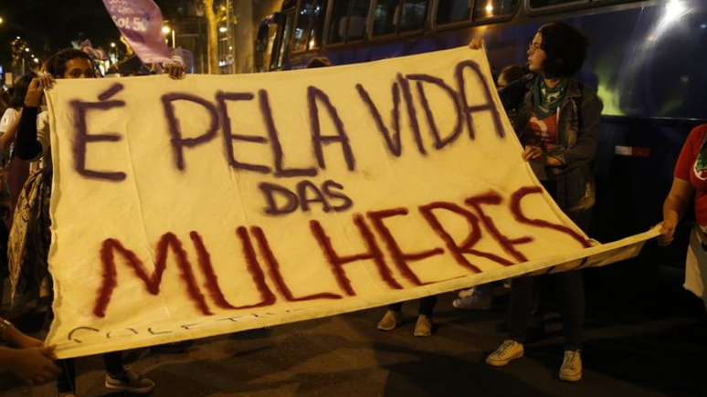 Mulheres levantam cartaz em protesto pela legalização do aborto