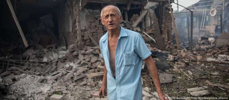 Morador de 71 anos de Soviansk observa a casa de seus parentes destruída  em ataque russo