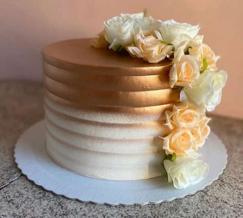 67. As rosas em branco e dourado trazem o toque delicado para o bolo de bodas de ouro. Fonte: Festas Biz