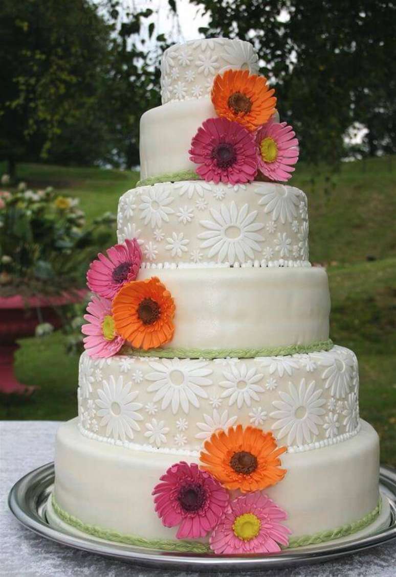 20. Bolo de festa decorado com fundo branco e flores de gérbera. Fonte: Elo7