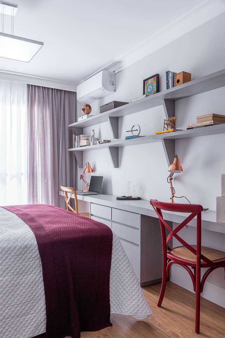 Se estendendo por toda a parede, as prateleiras acomodam objetos, livros e documentos dos moradores. Para setorizar o espa&ccedil;o de cada um, Carina desenhou um gaveteiro super funcional