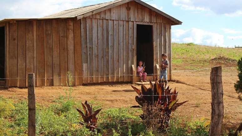 Foto de uma casa quilombola da comunidade Paiol de Telha. Na porta da moradia, estão duas crianças.