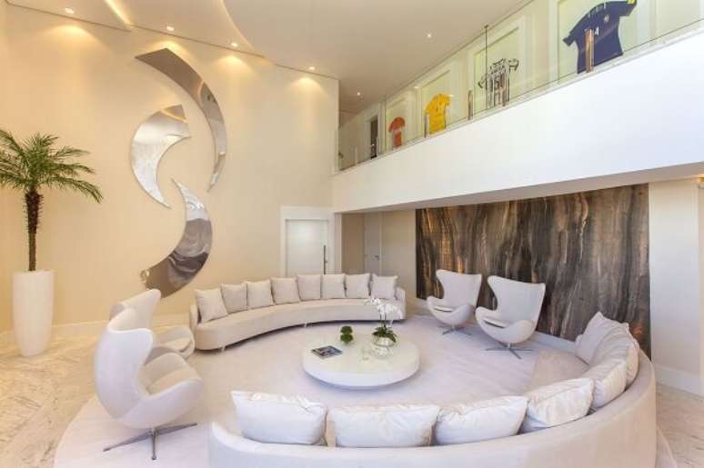 4. Sala de estar com porta de madeira branca e sofá curvo – Foto Iara Kilaris