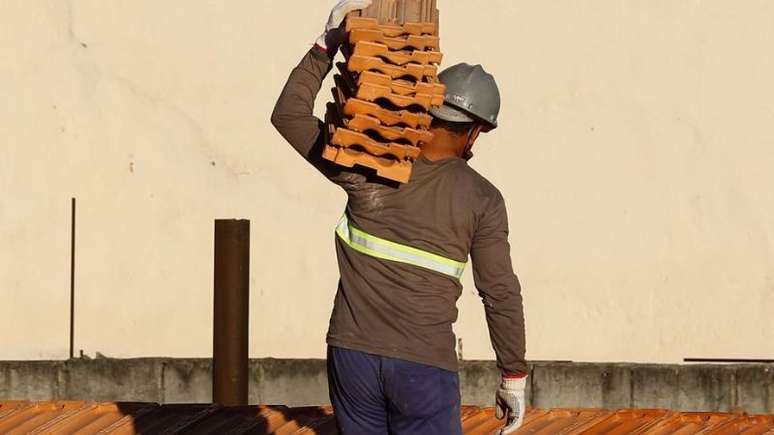 Imagem mostra um trabalhador negro carregando blocos de telha sobre o ombro. Os negros são as principais vítimas de acidentes de trabalho na Bahia.