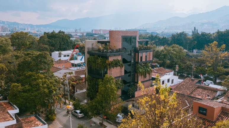 Fachada de pr&eacute;dio em destaque na paisagem do bairro, com montanha ao fundo.