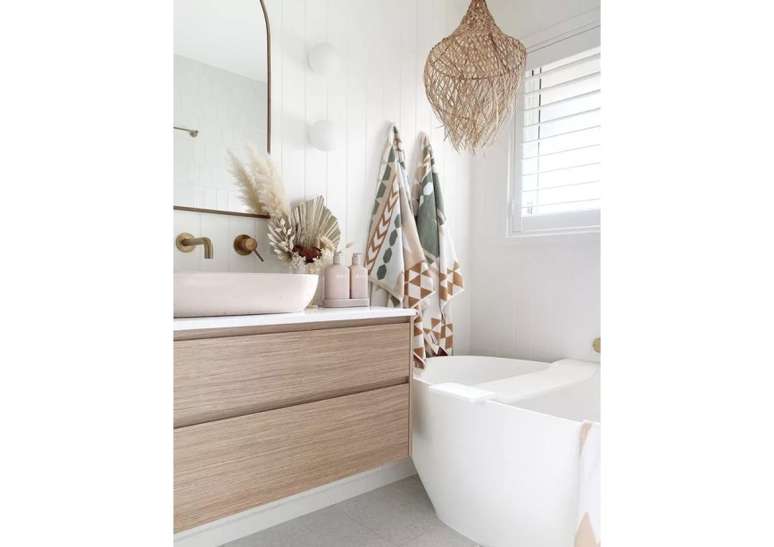 D&ecirc; um toque de decora&ccedil;&atilde;o boho ao seu banheiro costeiro, colocando toalhas com cores suaves e estampas geom&eacute;tricas e optando por uma lumin&aacute;ria tecida que praticamente funciona como obra de arte.