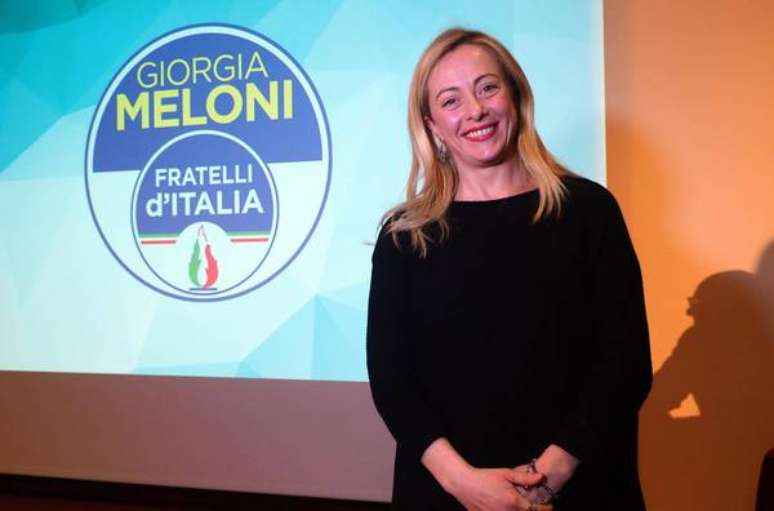 Giorgia Meloni com o símbolo do partido FdI e sua chama tricolor