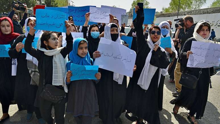 Mulheres e meninas afegãs participam de um protesto em frente ao Ministério da Educação em Cabul em 26 de março de 2022, exigindo que as escolas secundárias sejam reabertas para as meninas