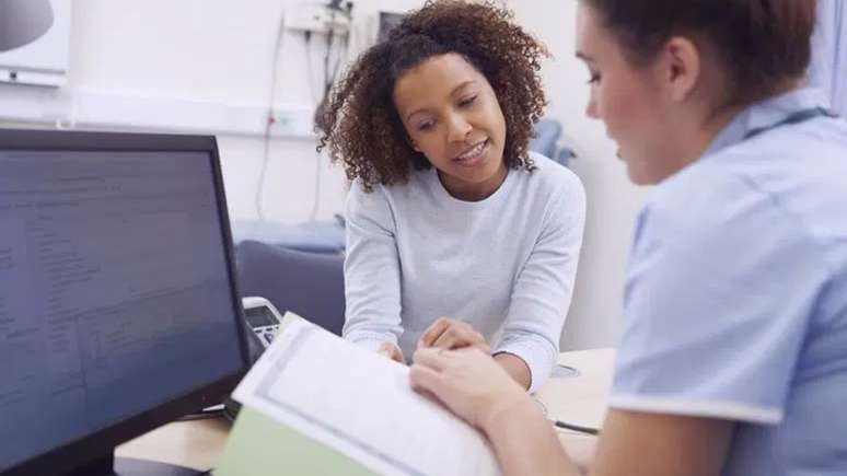 Imagem mostra uma mulher negra durante uma consulta médica.