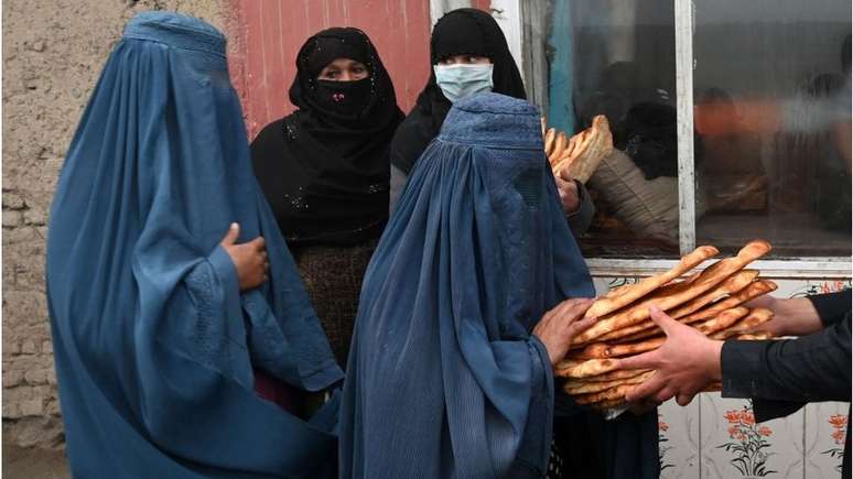 Mulheres vestindo burca recebem pão grátis distribuído como parte da campanha 'Salve os Afegãos da Fome em Cabul', no dia 18 de janeiro de 2022