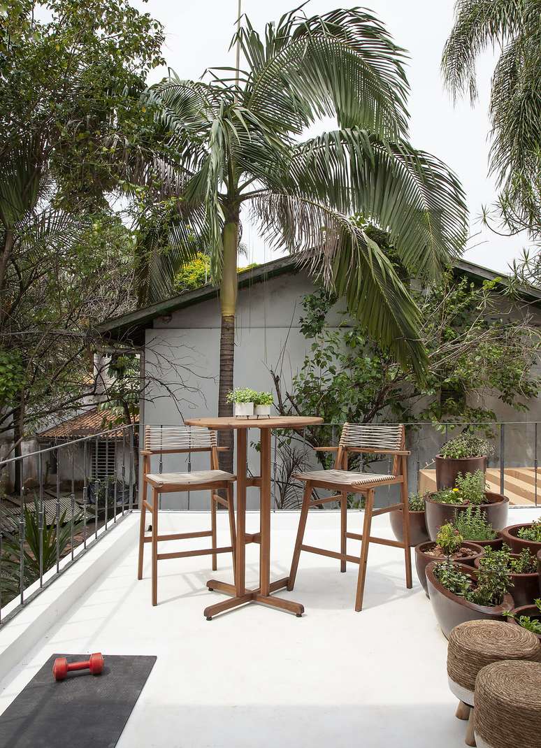 As banquetas altas e a mesa bistr&ocirc;, ambas de madeira, recebem os caf&eacute;s da manh&atilde; ao ar livre neste projeto de Bruno Moraes