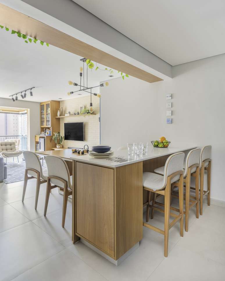 Em alta na decoração, a bancada do tipo ilha, presente em cozinhas e varandas gourmet, é a perfeita combinação com as banquetas altas. Neste apartamento, o arquiteto Bruno Moraes elegeu móveis com assento e estrutura de madeira arredondadas