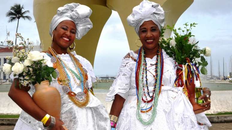 Imagem mostra duas mulheres de religião de matriz africana com roupas típicas brancas, em referência a Oxalá.