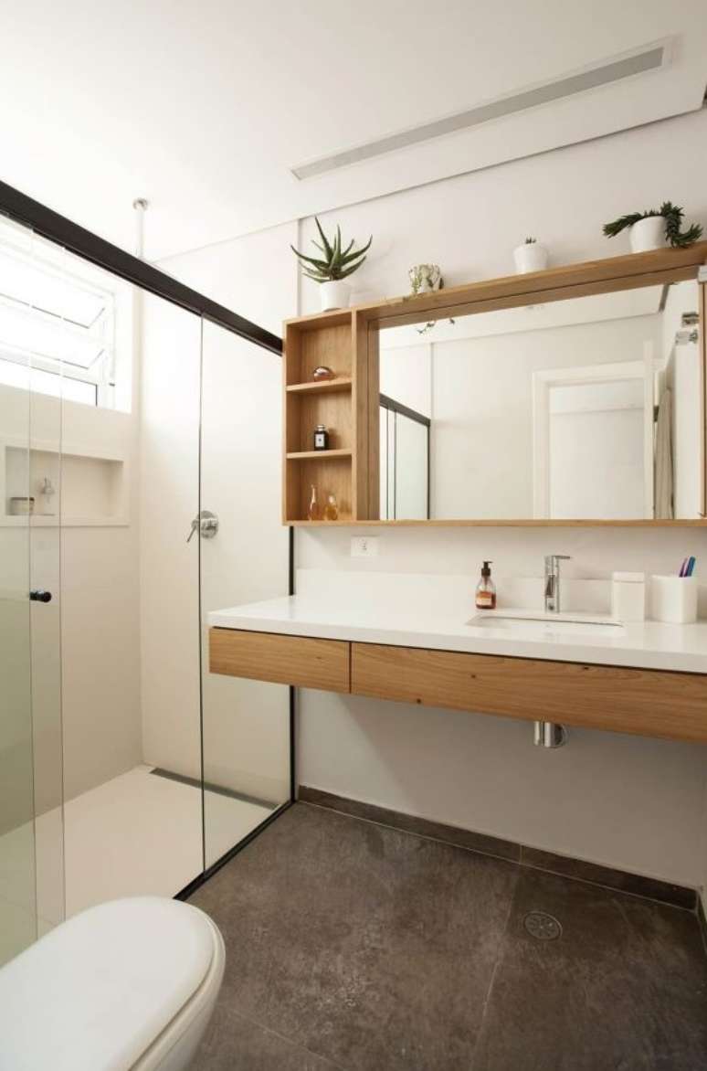 Banheiro com bancada e box em vidro