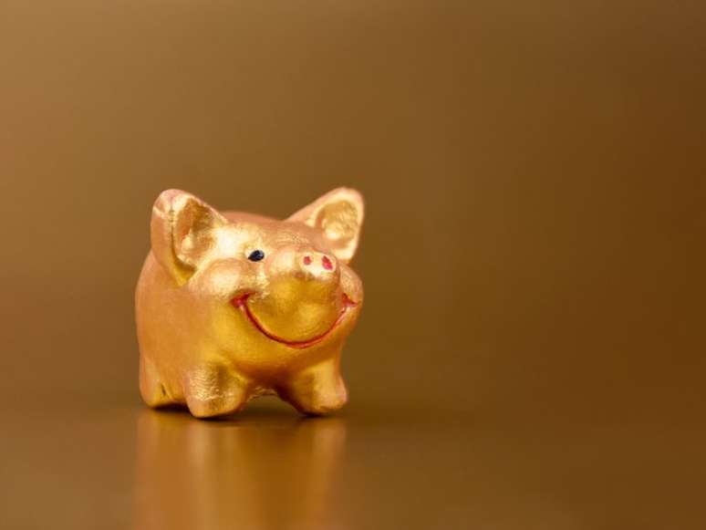 Golden piggy toy on a gold background frame stock images. Cute little pig figurine on a gold background with copy space for text stock images