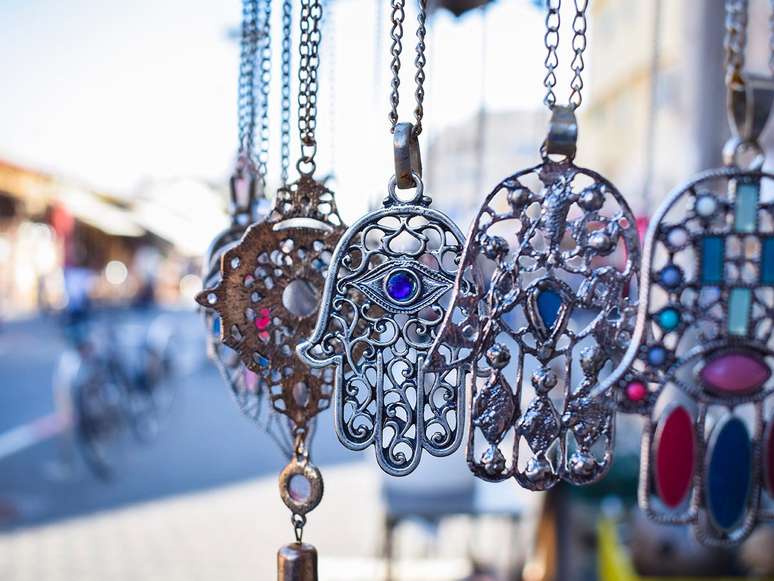 Close-up of Hamsa, also known as Fatima Hand or Hand of God necklace, pending on a flea market in Tel Aviv-Jaffa, Israel. Metal protection amulet.