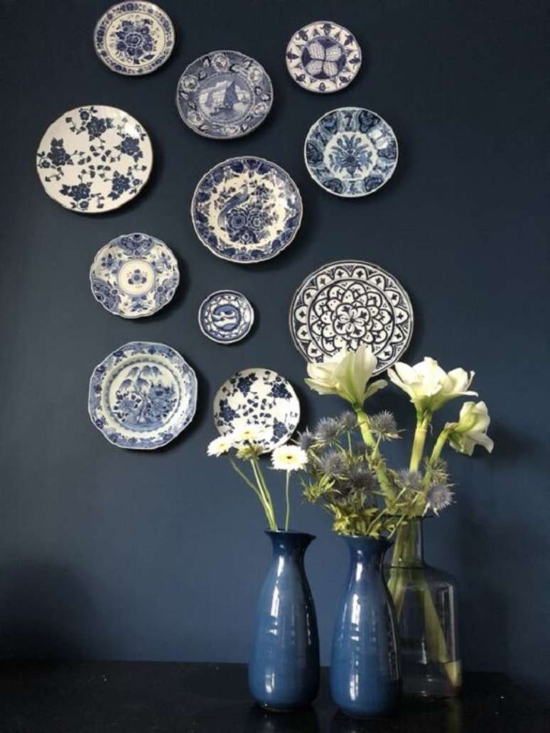 50. Os pratos decorativos criam um contraste interessante na parede escura. Fonte: Marijke
