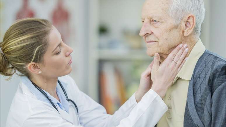 Um médico verifica os gânglios linfáticos de um homem mais velho.