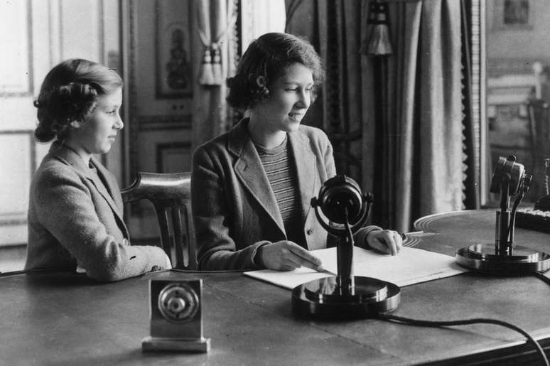 As princesas Elizabeth (dir.) e Margaret fazem uma transmiss&atilde;o nacional de r&aacute;dio durante a Segunda Guerra Mundial, em 1940
