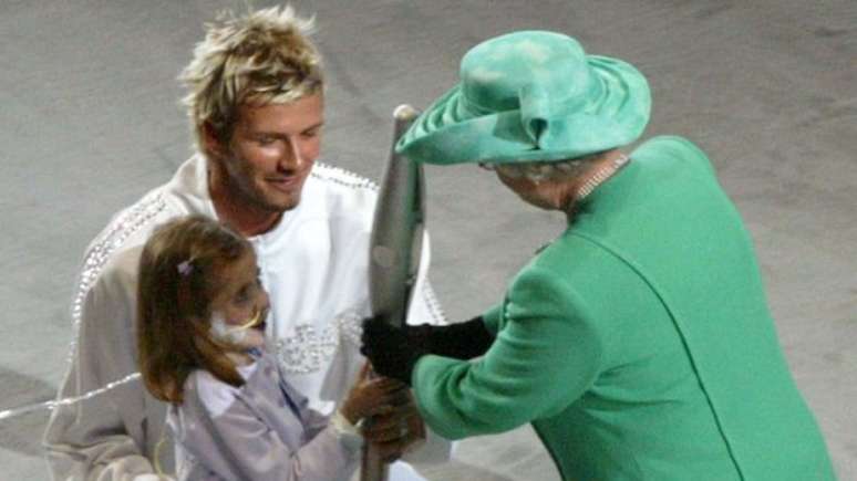 A rainha é homenageada por seu Jubileu de Ouro na cerimônia de abertura dos Jogos da Commonwealth de 2002 em Manchester por David Beckham e Kirsty Howard