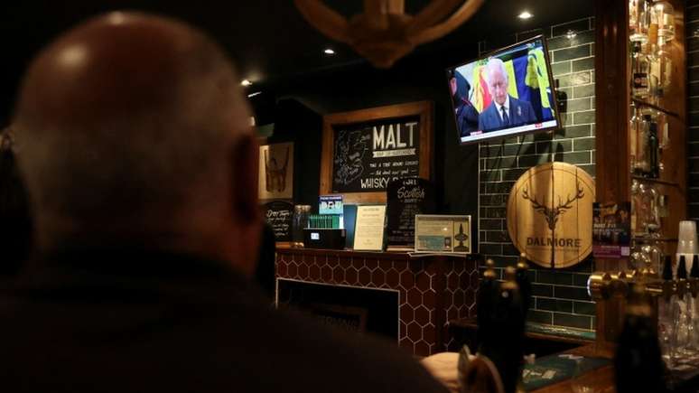 Homem acompanha cerimônia na TV no pub The Albanach, em Edimburgo