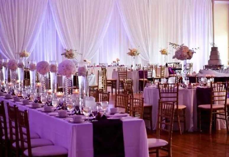 57. Decora&ccedil;&atilde;o de casamento com arranjos de flores e suportes de vidro para mesa