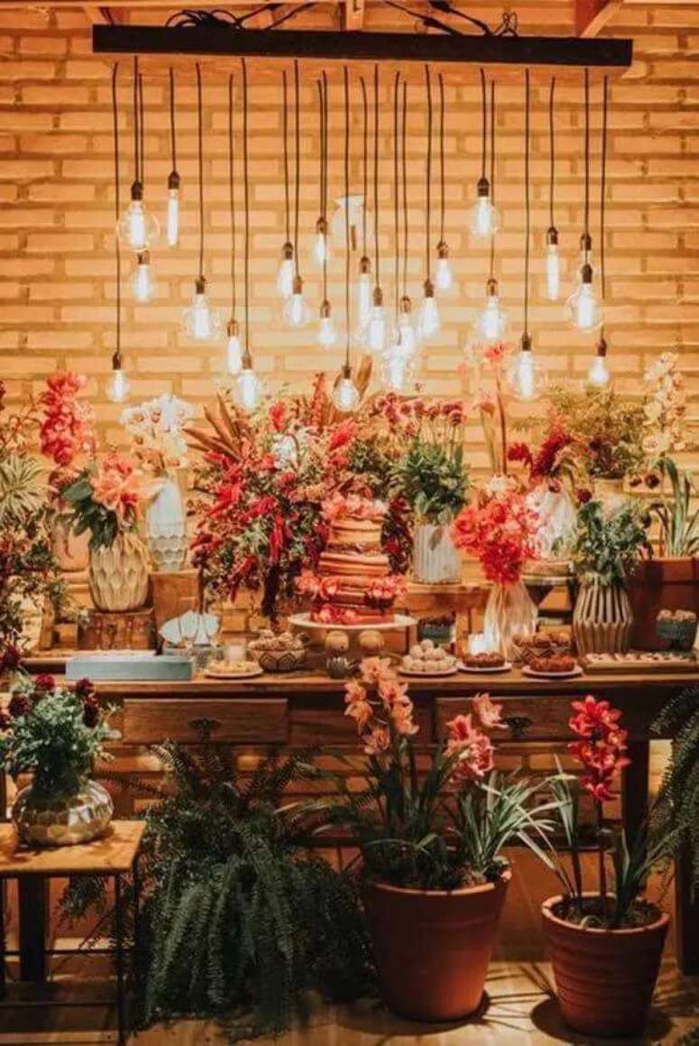 86. Decora&ccedil;&atilde;o de mesa de casamento r&uacute;stica com lumin&aacute;ria pendente e muitas flores &ndash; Foto: L&aacute;pis de Noiva
