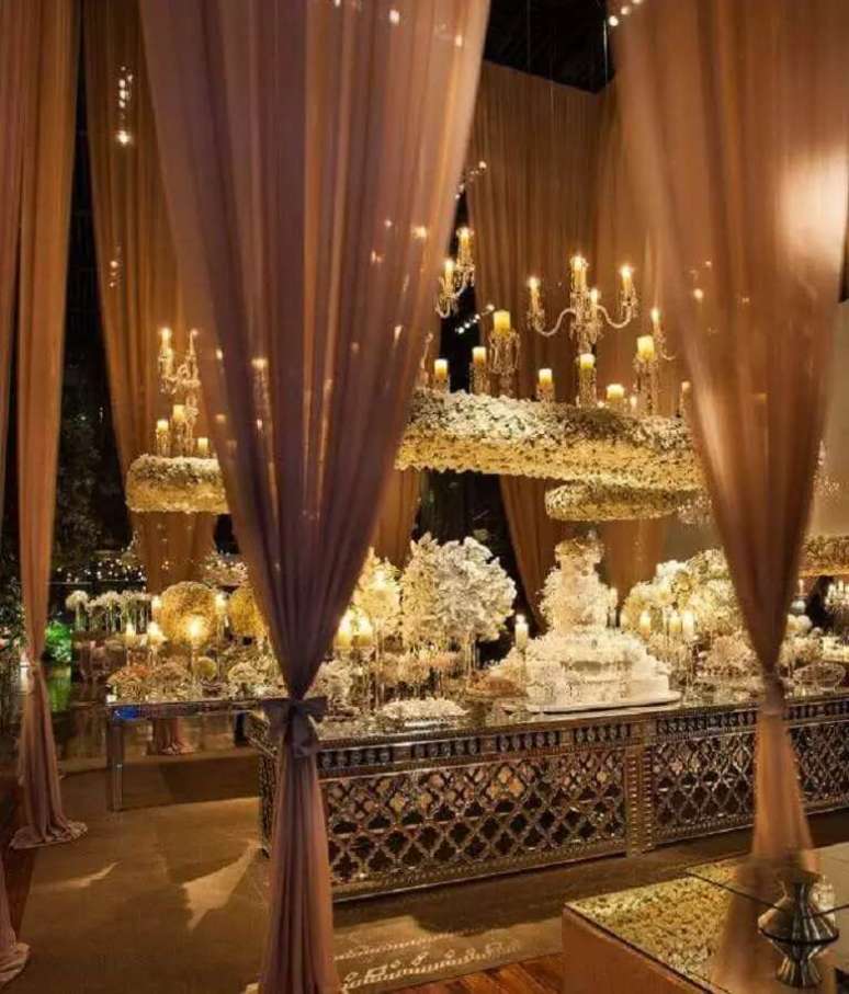 10. Decora&ccedil;&atilde;o de casamento sofisticada com muitas flores e casti&ccedil;ais decorando a mesa do bolo.
