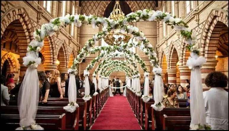 27. Decora&ccedil;&atilde;o de igreja para casamento com arcos de flores brancas